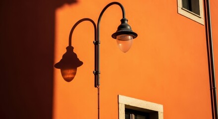 Vintage street lamp casting shadow on vibrant orange wall in urban setting