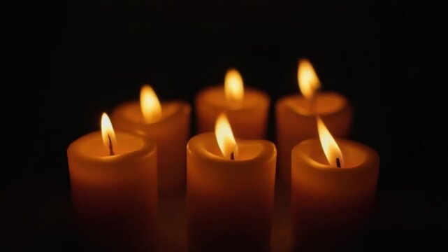 Five softly glowing candles gently illuminate the surrounding darkness, creating a calm and peaceful atmosphere