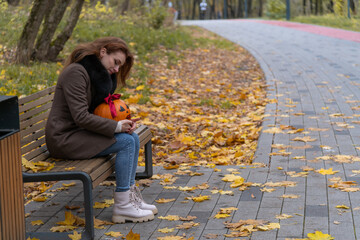 Festive autumn moment with carved pumpkin and joyful woman in park