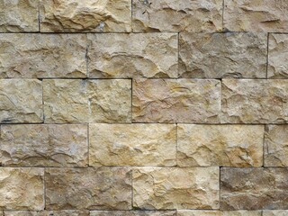 A close-up, detailed view of an ornate stone wall, showcasing the rough, natural texture and varied colors of each block.