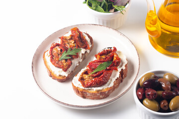 Two bruschettas with dried tomatoes, ricotta cheese and rucola on ciabatta bread. 