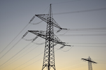 High-voltage electricity pylon photographed from below at blue hour shortly after sunset, silhouetted against the evening sky in Germany.