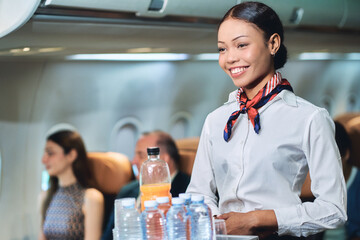 Focus on airhostess smile for service passenger with soft drink in airplane service.