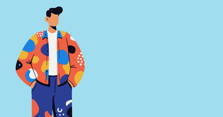 A stylish man in a vibrant, patterned jacket stands confidently with hands in pockets against a clean, light blue background, showcasing modern fashion trends.