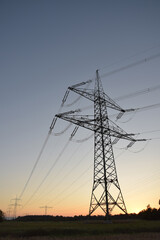 High-voltage electricity pylon photographed from below at blue hour shortly after sunset, silhouetted against the evening sky in Germany.