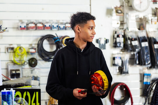 Young male mechanic holding a mining vehicle light inside workshop testing parts before installation