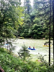 People kayaking on a calm river surrounded by forest in Turnau, Austria. Scenic outdoor adventure and travel nature scene in the Austrian Alps.