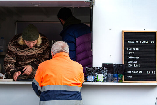 Workman buying warm drink before work from small business coffee van