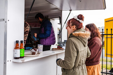 Young women buying warm drinks on winter morning form small local business