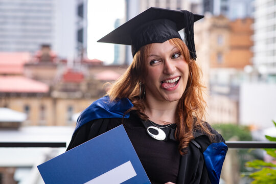 fun genZ graduate making a funny face as she poses with her graduation certificate