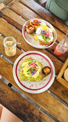 Two slice of sourdough bread toastwith avocado paste with black pepper and egg white crab meat on another slice. Lemon slice on the side on a white plate