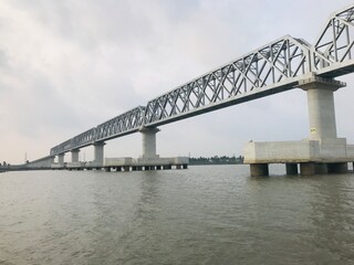 Long steel truss railway bridge crossing a wide river under a cloudy sky