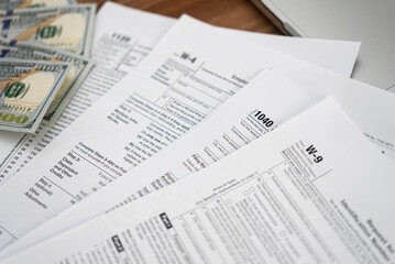 Obraz premium Dollar bills placed on various tax forms indicate concept of complicated process of filling documentation in compliance with law and need for assistance service