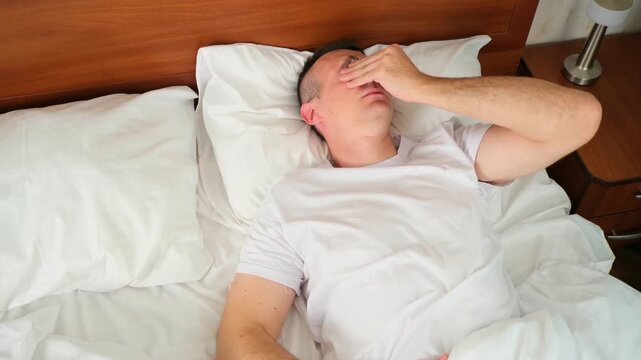 Caucasian man wake up sleeply in bed
