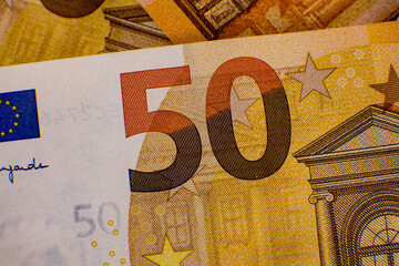 Detailed view of a fifty euro banknote featuring vibrant colors and intricate designs on a textured surface in a close-up perspective