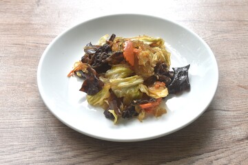 fried glass noodles with black ear mushroom and cabbage in black sweet soy sauce on plate