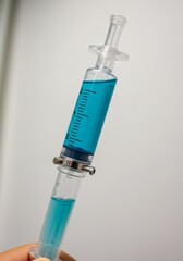 Blue Liquid Filled Syringe Held by a Hand