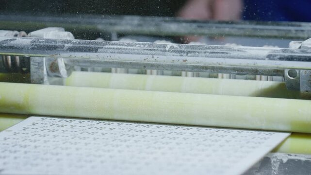 Professional braille printer mechanically embossing raised text onto paper, generating tactile reading materials enabling independent access to information for visually impaired individuals