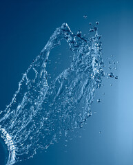 Obraz premium Splash of water frozen mid-air against blue background, showing fluid motion and surface tension.