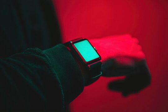Businessman's wrist adorned with a luxury smart wearable, glowing holographic interface projected above, minimalist black background, sharp lighting. - Powered by Adobe