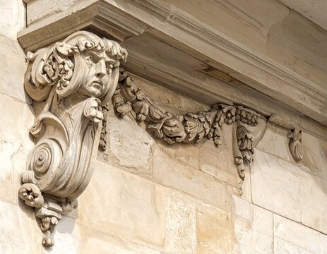 Intricate architectural corbel featuring a human face and decorative foliage on a stone facade