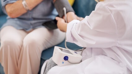 Doctor measuring blood pressure of senior woman at home