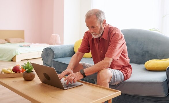 Senior man working remotely on laptop at home