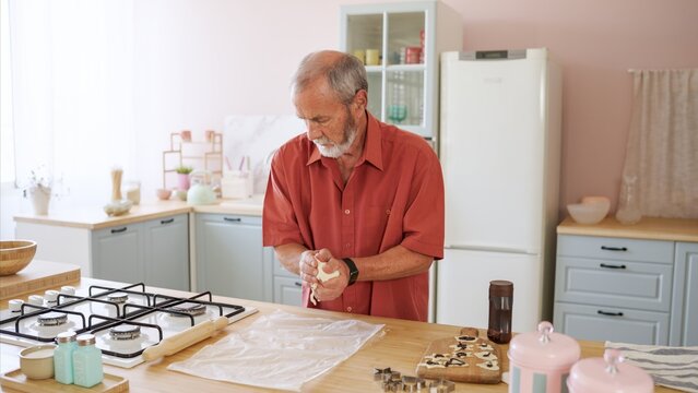Senior man kneading dough, baking in modern kitchen