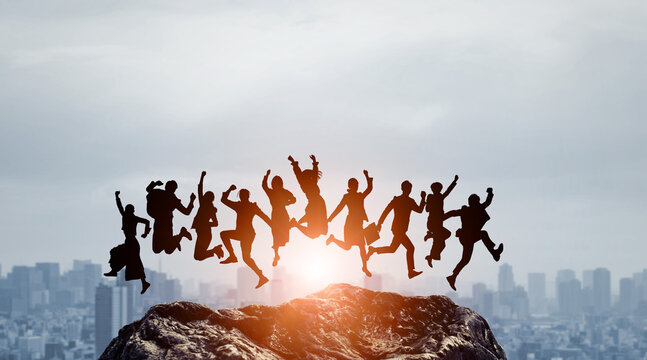 Silhouettes of people of various attributes jumping against the backdrop of the city. Wide angle visual for banners or advertisements.