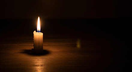 Single lit candle in dark room symbolizing hope and faith