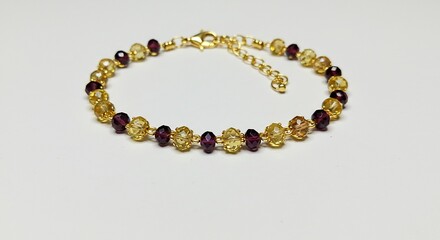 Obraz premium Elegant gold anklet delicately adorned with garnet beads shines brightly. AI Generated