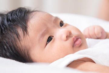 Asian newborn baby lying with teddy bear while mother gives gentle care, reflecting family bonding, parental love, home lifestyle, child wellness, protection, nurture, and childcare development