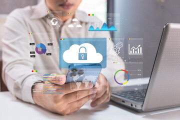 A person interacts with a smartphone displaying cloud technology and data analytics, while a laptop is present, highlighting digital connectivity and cybersecurity.