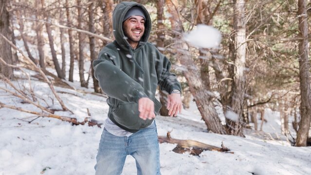 Young man throwing snowball in snowy forest - Powered by Adobe