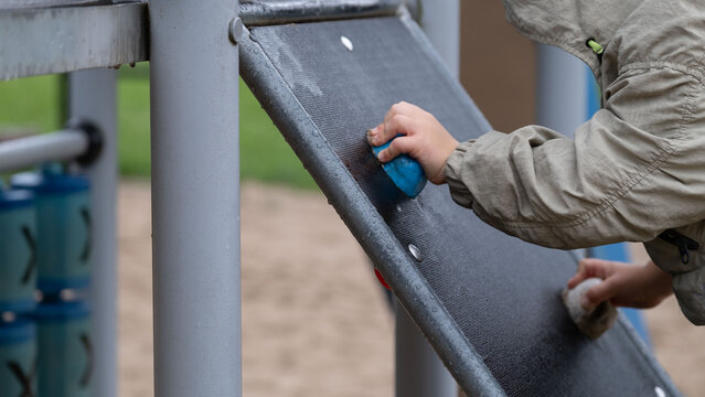 Child climbing ramp on playground with hand grips