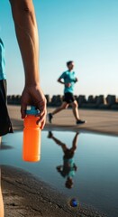 Runner pauses with water bottle after a workout, Runner reflects in puddle after exercise on a sunny day