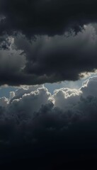 Obraz premium Dramatic Clouds Looming Overhead with Sunlight Peeking Through Creating a Contrast of Light and Shadow Across a Stormy Sky