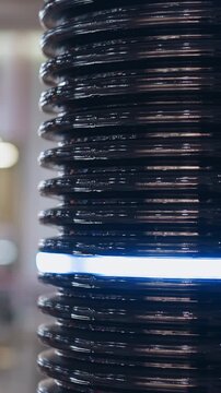 Black corrugated plastic pipe with glowing led ring installed as decorative element on blurred background in spacious shopping mall closeup