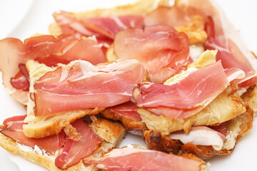 Delicious croissant sandwich snack. Slices of schwarzwald ham on crispy croissant bread. Fingerfood appetizer with traditional German ham. Fresh tasty starter for party. Easy gourmet food.