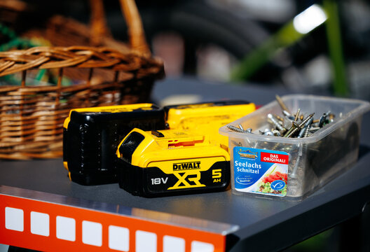 Faaker See, Austria - September 01, 2025: DeWALT battery packs and screws displayed on a table with a wicker basket in the background, showcasing tools and hardware for DIY projects