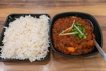 White basmati rice came with delicious spiced chicken tikka masala dish in black bowl with garnishes.