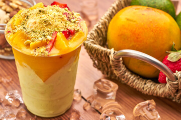 Avocado and Mango Smoothie with Pistachios, Strawberries, and Vanilla Ice Cream in glass side view of healthy drink