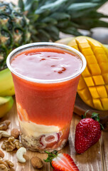 Strawberry Mango Layered Smoothie with Nuts and Fresh Fruit in glass side view of healthy drink