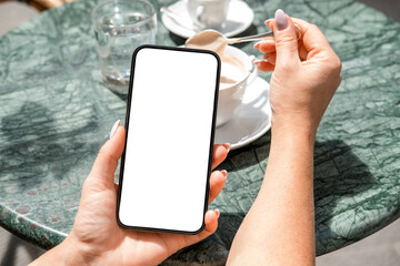 Smartphone mock up with blank screen held by woman in cafe, enjoying coffee and relaxing at a stylish outdoor table setting