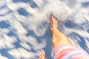 Blick auf die Füße beim Gehen über einen Strand mit Bewegungsunschärfe