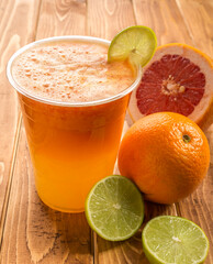 Fresh Orange, Grapefruit, and Lime Juice with a Lemon Slice Garnish in glass on wooden table side view of fresh drink