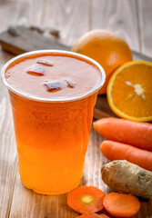 Fresh Orange and Carrot Juice with Ginger in glass on wooden table side view of fresh drink