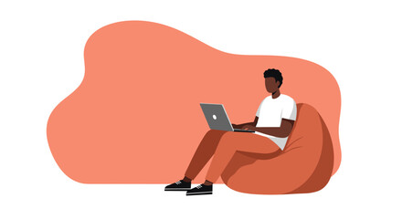 Young man working on laptop from home, sitting comfortably on a bean bag chair. Ideal for remote work, freelance, or online education concepts.
