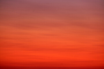 A smooth gradient sky with warm red, orange, and purple tones at sunset, ideal for backgrounds, textures, or design projects.