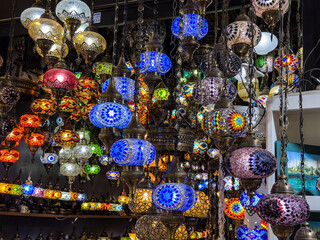 Traditional mosaic lamps glowing in colorful display at bazaar shop. Culture, craft, and heritage representing art, decoration, and tourism lifestyle.